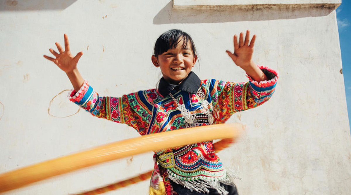 China: Ein lachendes Mädchen schwingt einen Hula-Hoop-Ring.