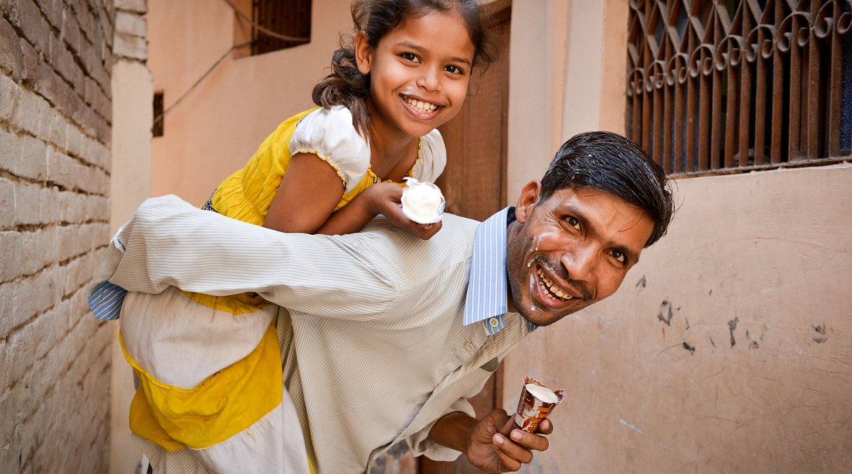 Indien: Ein Vater trägt seine Tochter auf dem Rücken.