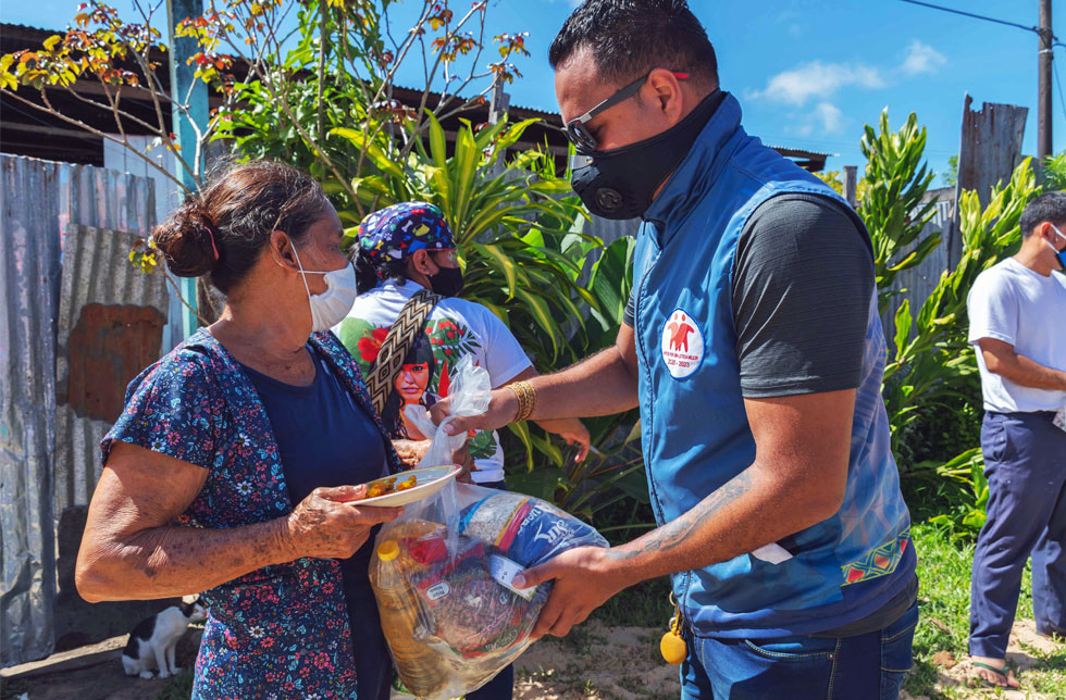 Ein Helfer gibt einer Frau in Kolumbien ein Nahrungspaket.