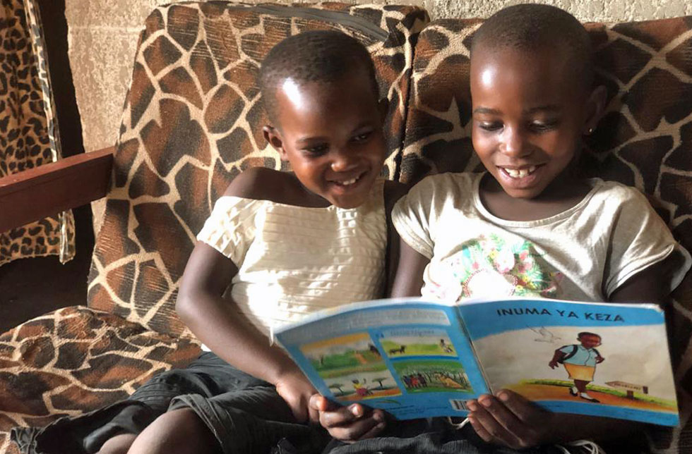 Zwei Mädchen in Ruanda lesen gemeinsam ein Buch. 