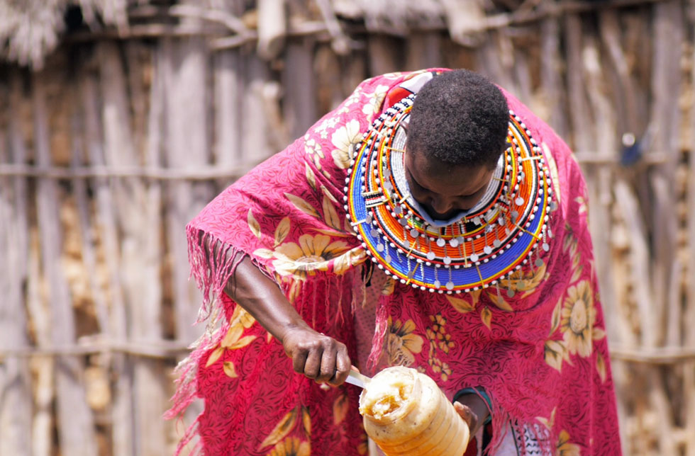  Eine Masai-Frau mit Perlenschmuck leert ein Honigglas. Text: World Vision Schweiz