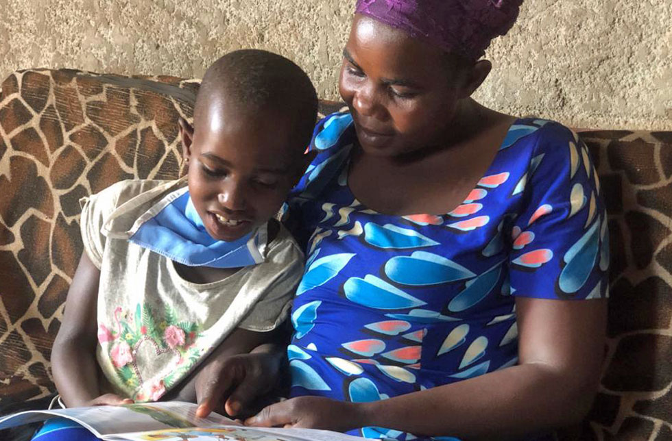 Ruanda: Eine Mutter liest mit ihrer Tochter ein Buch.