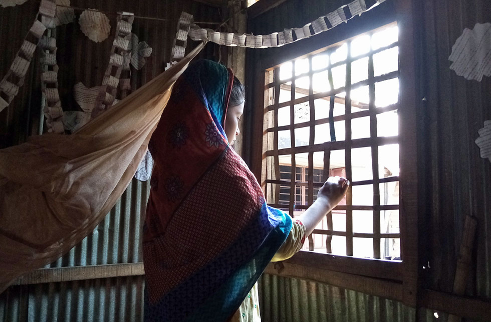 Ein Mädchen in einem Slum in Rangpur, Bangladesch, schaut aus dem Fenster.