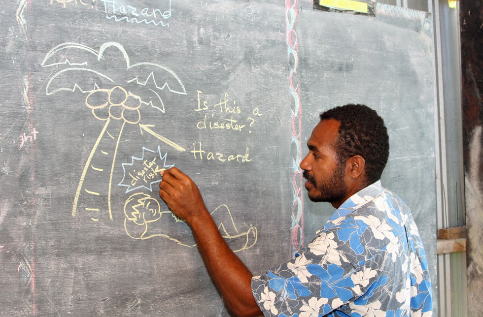 Ein Lehrer in Papua Neu Guinea zeigt Kindern mit Bildern, wie man sich auf Katastrophen vorbereitet.