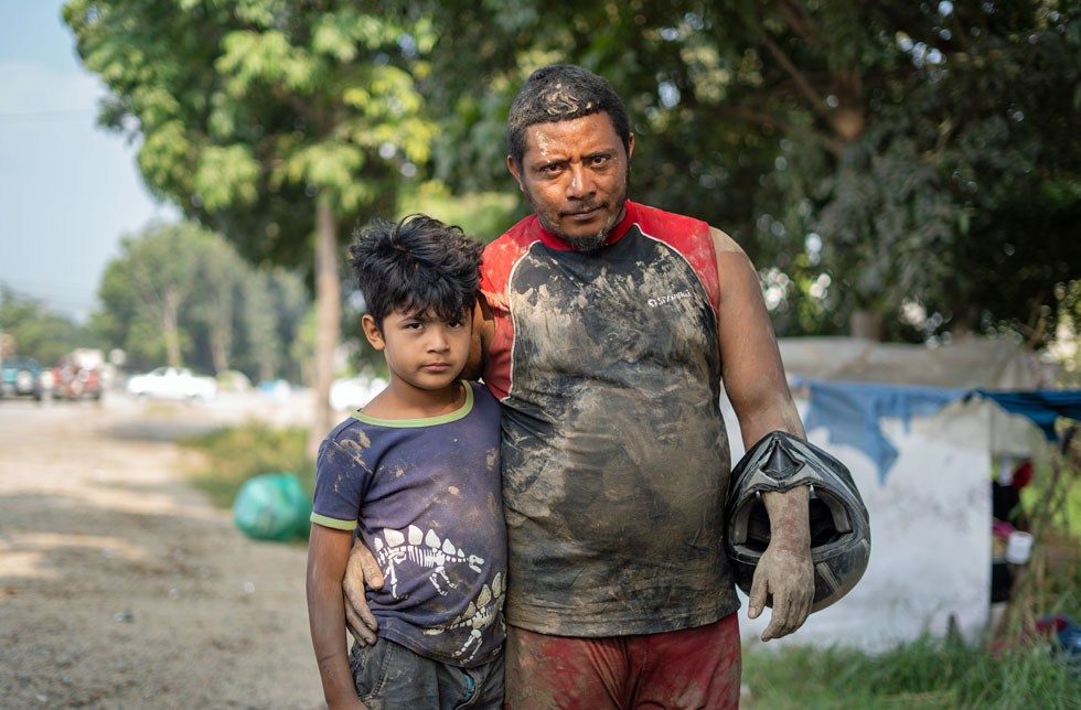 Honduras: Ein Junge und sein Vater in von der Überschwemmung verschmutzter Kleidung.