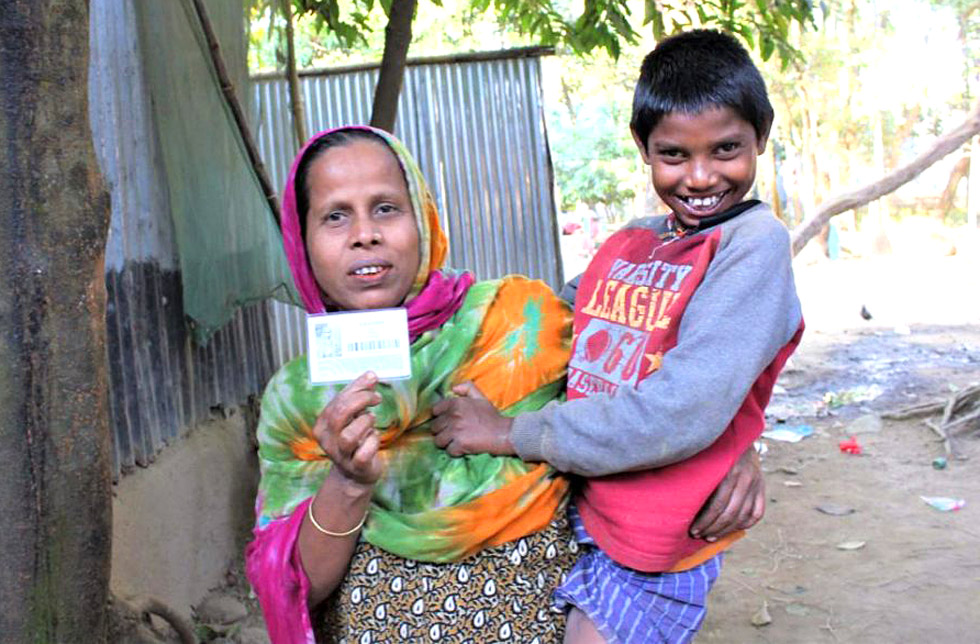 Eine Mutter in Bangladesch zeigt ihre Nothilfe-Karte, mit der sie Hilfsgüte beziehen kann.