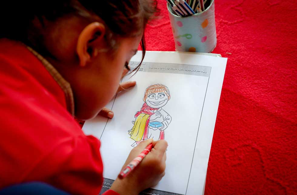 Afghanistan: Ein Mädchen malt in ein Schulheft. Bildung, Schule, Schulverbot