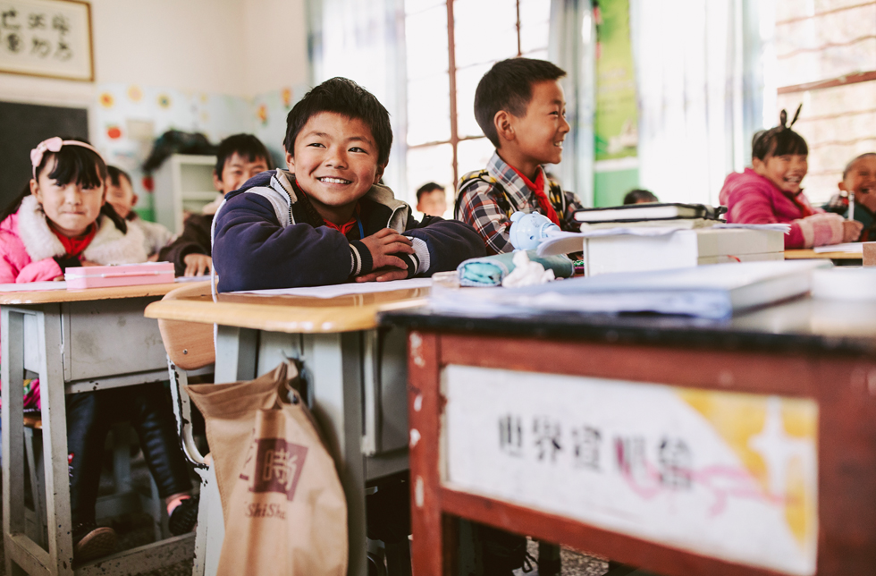 China: Ein Junge sitzt zusammen mit seinen Klassenkameraden/-innen im Schulzimmer.