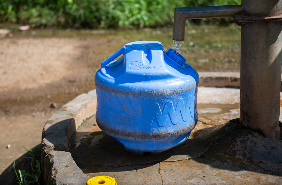 Indien: Ein blaues Kunststoffgefäss, das mit Wasser befüllt wird.