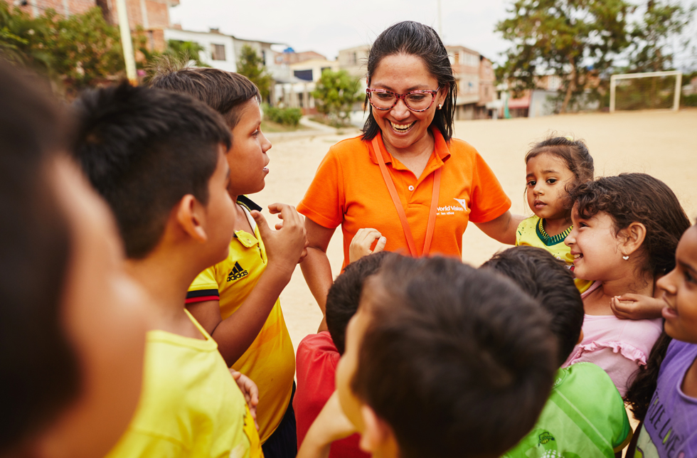 Kolumbien: Eine World Vision-Mitarbeiterin wird umringt von Kindern.