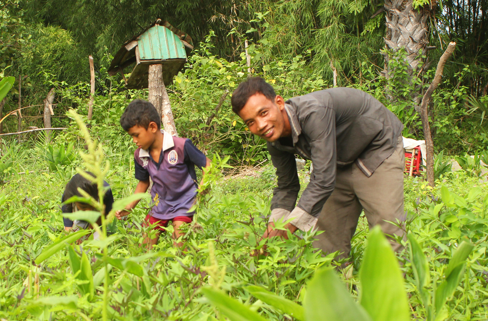 ein Vater mit seinen Kinder auf einem Gemüsebeet in Kambodscha