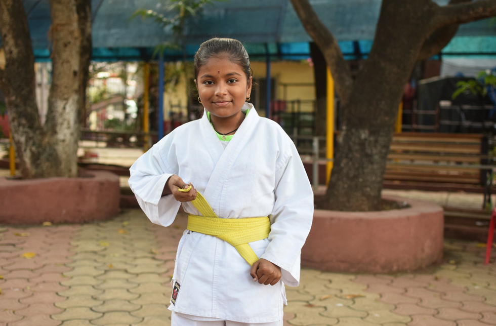 Indien: Ein Mädchen in Karateuniform ist in Kampfposition.