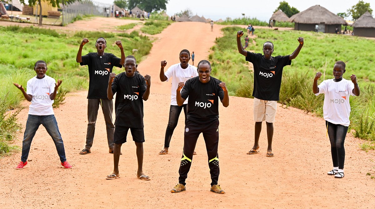 Uganda: jugendliche Mitglieder eines Medienclubs von World Vision stehen auf der Strasse und rufen laut.
