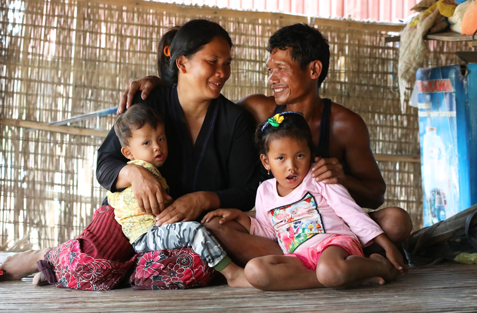 Eine vier-köpfige Familie sitzt in Kambodscha in einer sehr einfachen Hütte