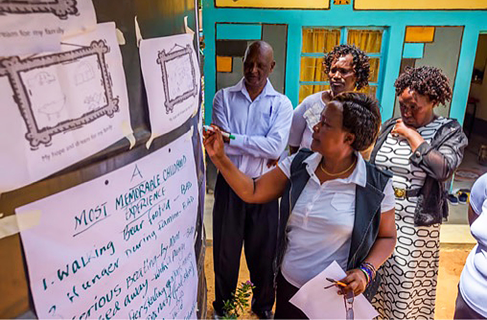Vier Personen stehen in Kenia vor einer Wand mit Flipchartbogen
