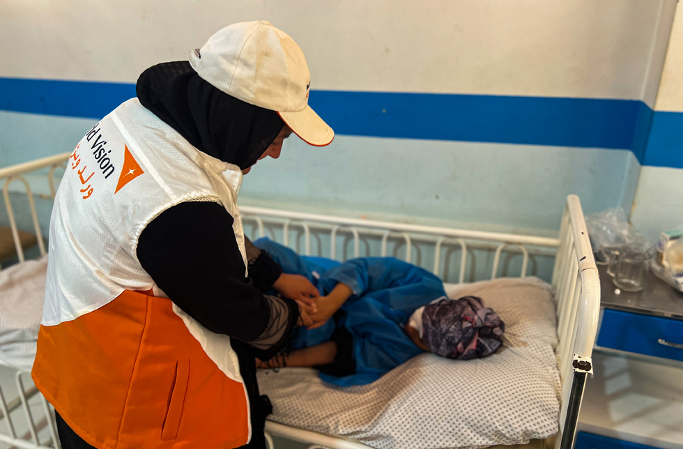 Afghanistan: Eine World Vision-Mitarbeiterin kümmert sich um ein verletztes Kind im Krankenbett.