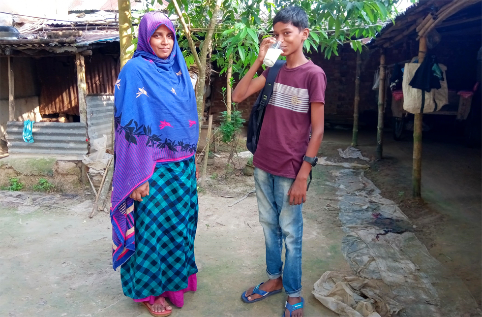 Bangladesch: Ein Junge trinkt ein Glas Milch, seine Mutter steht daneben.