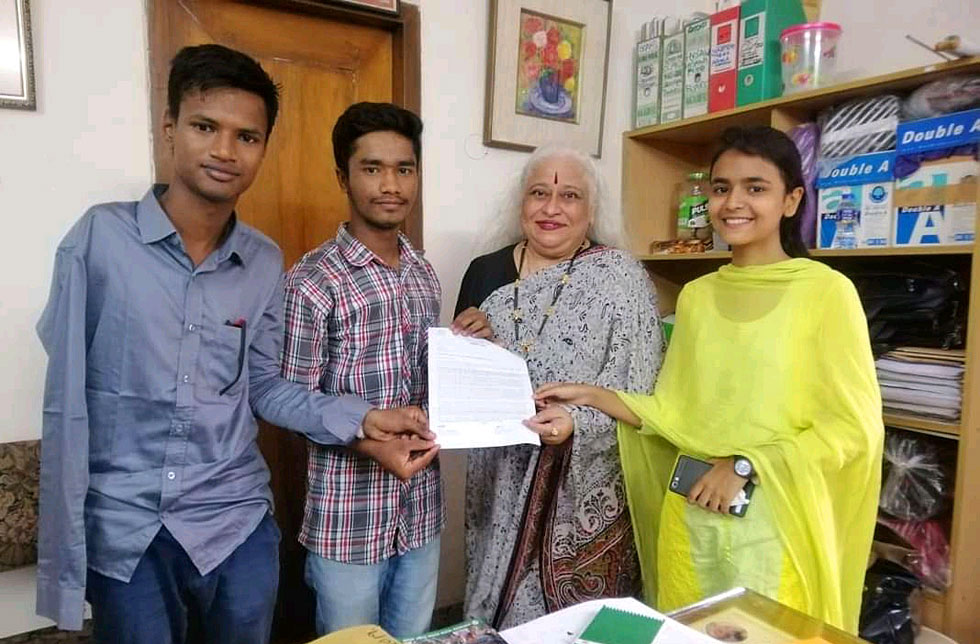 Bangladesch: Vier Personen zeigen ein Blatt Papier. Dem einen jungen Mann fehlt der rechte Arm.