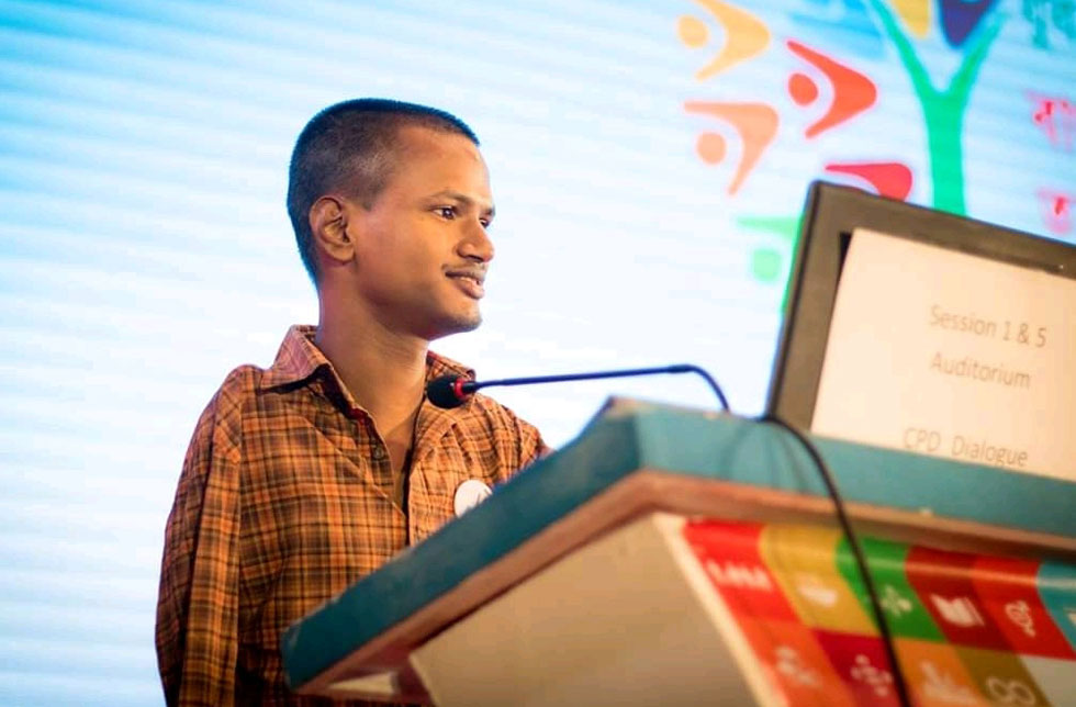 Bangladesch: Ein junger Mann steht an einem Rednerpult, das mit den Symbolen der Globalen Entwicklungsziele versehen ist.