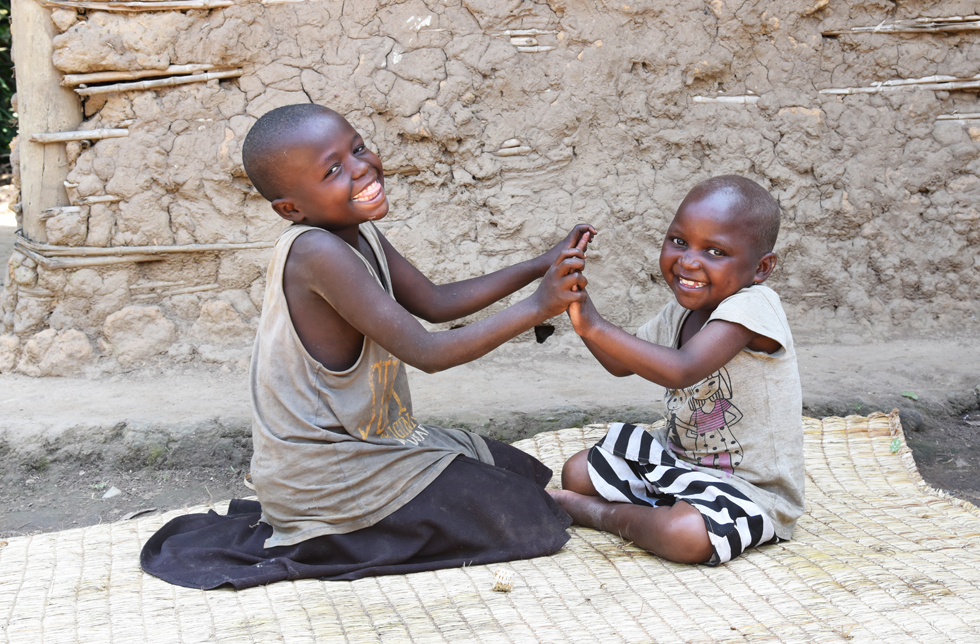 Demokratische Republik Kongo: Zwei Mädchen sitzen auf dem Boden und spielen ein Händeklatschspiel.
