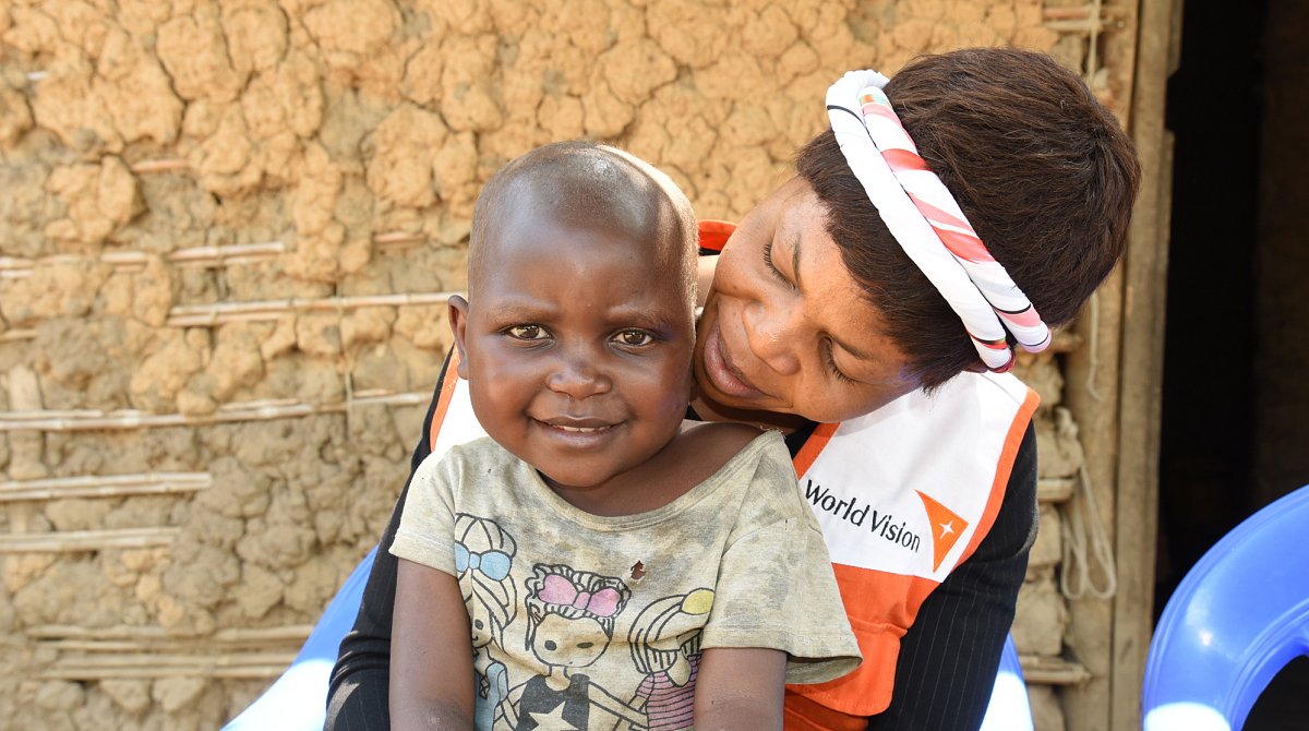 Demokratische Republik Kongo: Eine World Vision-Mitarbeiterin hält ein Kind auf ihrem Schoss.