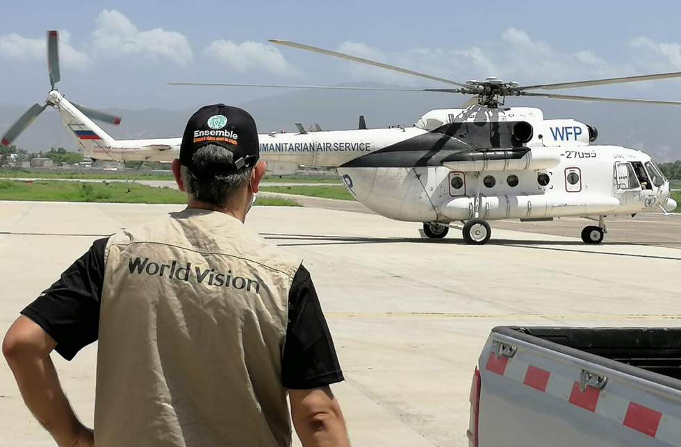 Ein World Vision-Mitarbeiter blickt auf einen Helikopter am Startfeld.