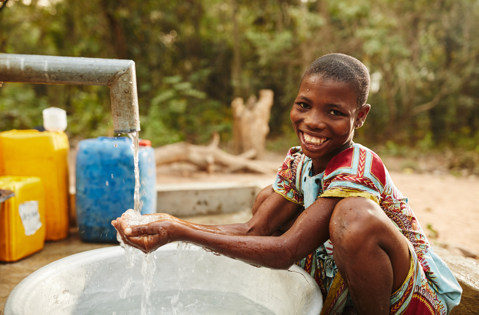 Ghana : une jeune fille puise de l'eau au robinet qui coule.