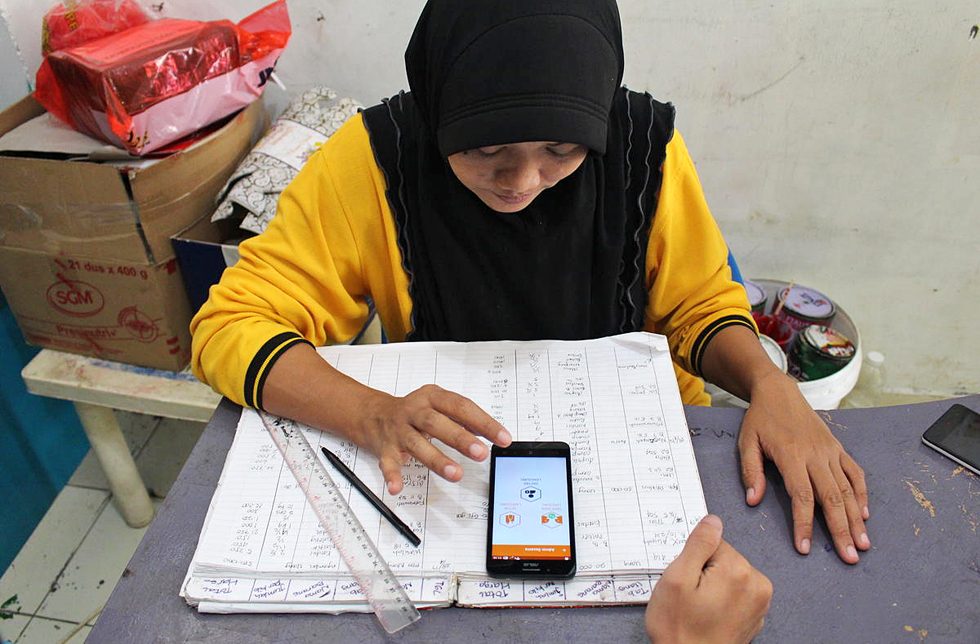 Ein Mädchen in Indonesien mit einem Mobiltelefon auf ihrem Schulheft.