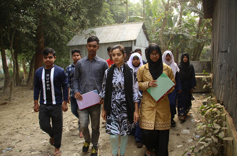 Bangladesch: Eine Gruppe von jungen Frauen und Männern ist auf einer Dorfstrasse unterwegs.