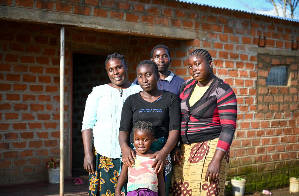 Sambia: Eine Familie steht vor ihrem solide gebauten Haus.