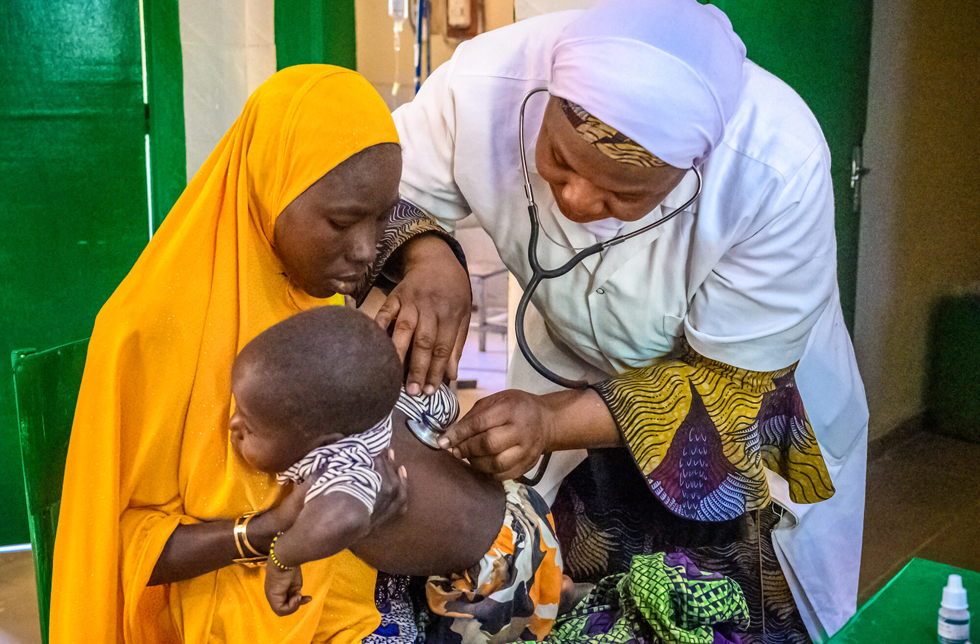 Niger: Eine Ärztin untersucht ein Baby, das von seiner Mutter gehalten wird.