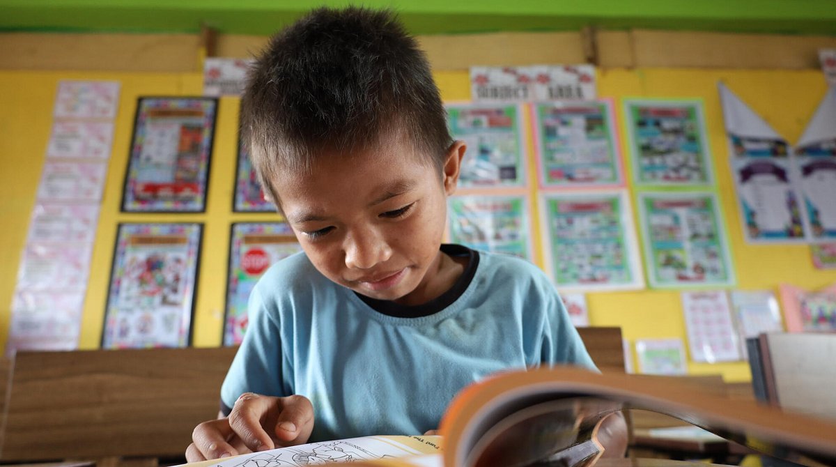 Philippinen: Junge im Klassenzimmer beugt sich über ein Buch.