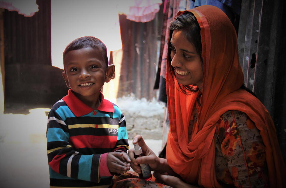 Bangladesch: Eine Mutter säubert die Hände ihres Sohnes mit einer Sprühflasche.