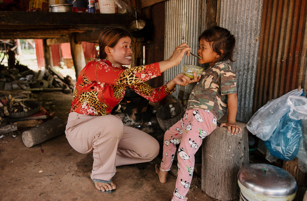 Kambodscha: Eine Frau gibt ihrer Tochter mit dem Löffel zu essen.