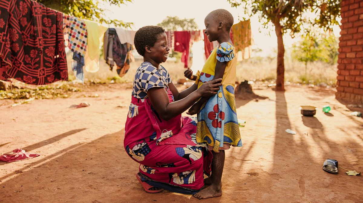 Malawi: Eine Mutter kniet nieder, um auf Augenhöhe mit ihrer Tochter zu sein.