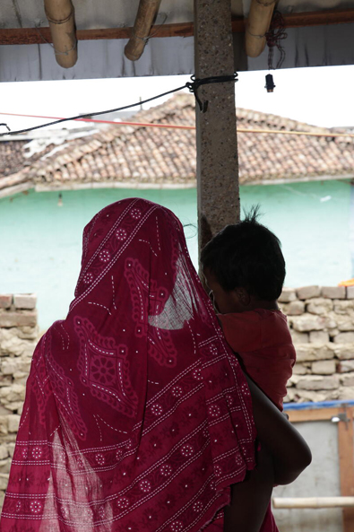 Bangladesch: Eine junge, verschleierte Frau hält ein Kleinkind am Arm.