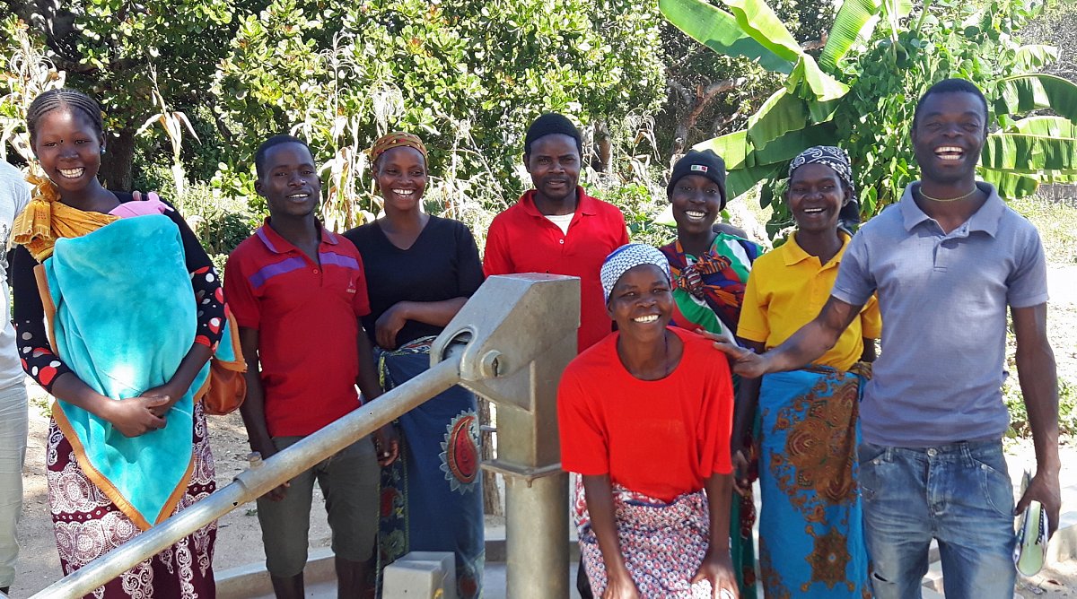 Brunnen und lachende Dorfbewohner in der Provinz Nampula, Mosambik.