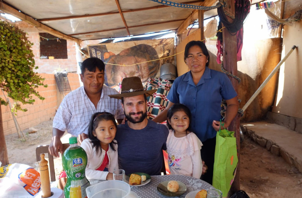 Bolivien: Ein Mann sitzt mit zwei Mädchen und deren Eltern an einem gedeckten Tisch. Auf den Tellern hat es Karottenkuchen.