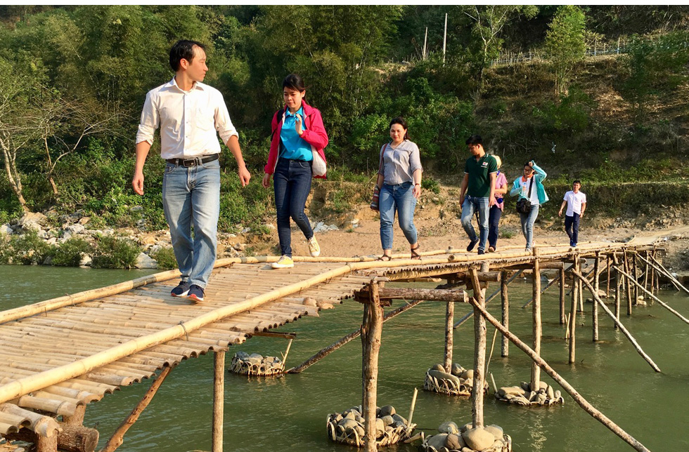 Vietnam: Eine Gruppe überquert auf einer Bambusbrücke einen Fluss.