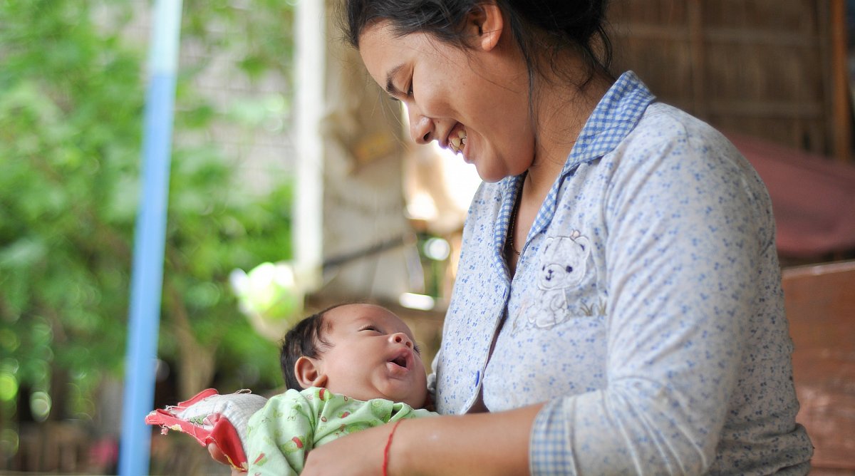 Mutter in Kambodscha stillt ihr neugeborenes Kind.