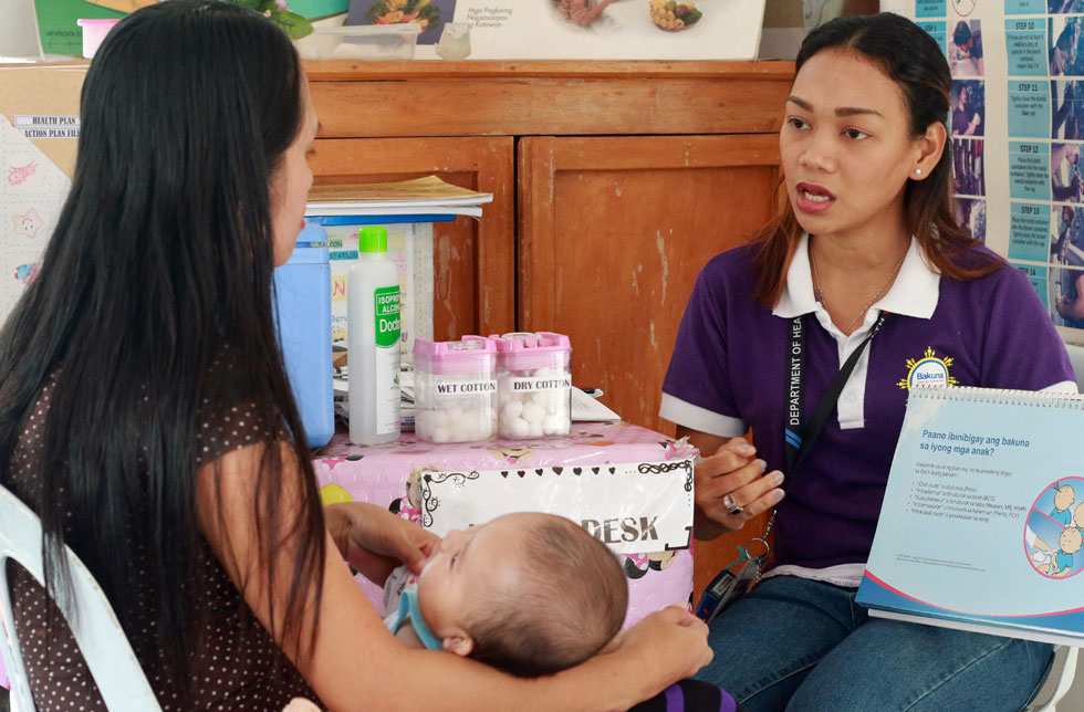 Eine Gesundheitsberaterin in den Philippinen spricht mit einer Frau mit Kind.