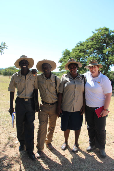 Simbabwe: Vier World Vision Mitarbeiter stehen lachend beisammen und blicken in die Kamera. Drei haben beige Kleidung an. Alle tragen Safari-Hüte.