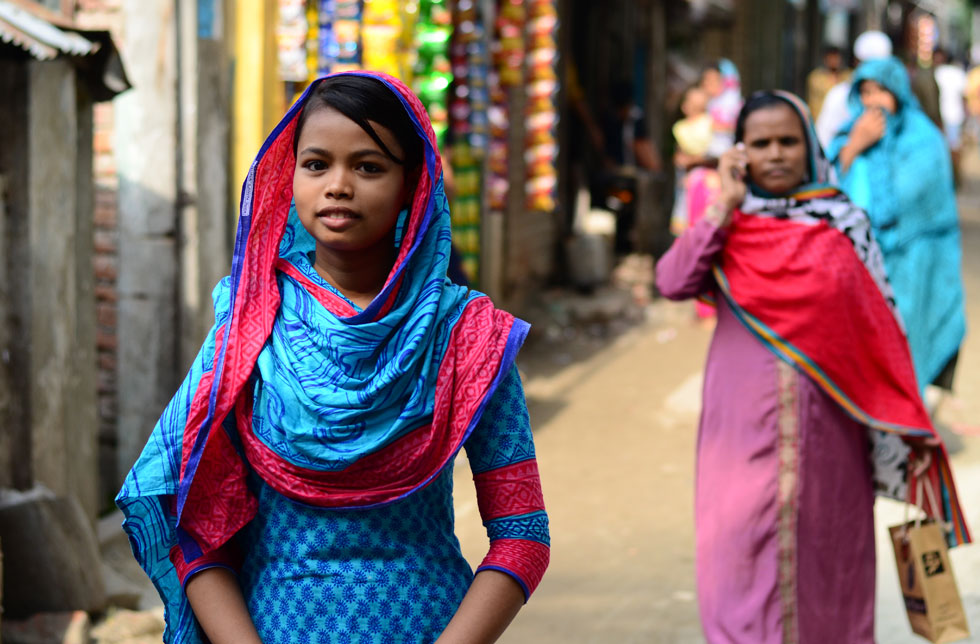 Bangladesch: Ein junges Mädchen steht in einer Strasse und blickt lächelnd in die Kamera.