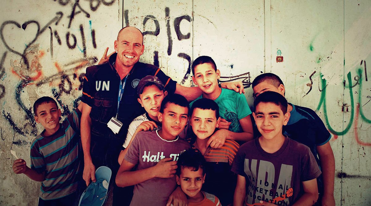 Naher Osten: Fröhliche Kinder vor einer bemalten Wand, mittendrin Christoph als UN-Mitarbeiter