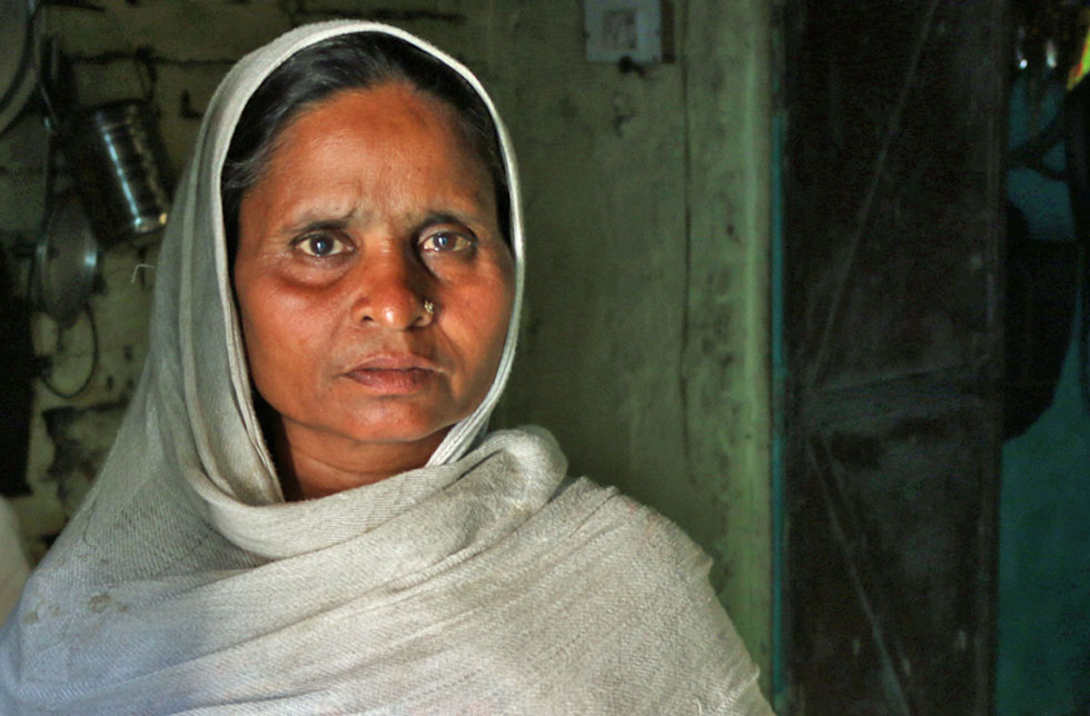 Indien: Eine Frau mit einem weissen Kopftuch blickt nachdenklich in die Kamera.
