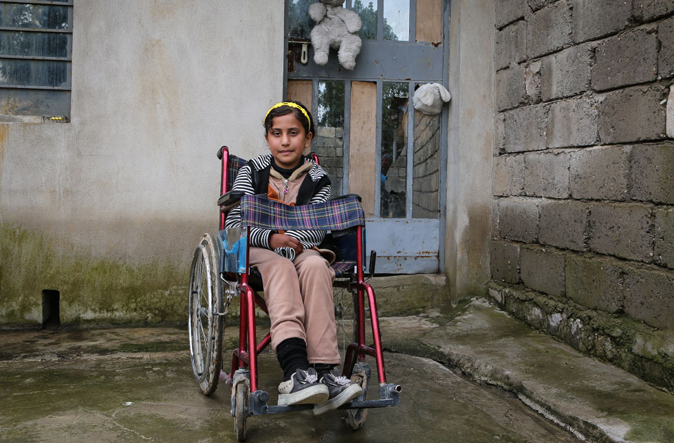 Mossul, Irak: Ein Mädchen sitzt in einem Rollstuhl in einem Vorhof.
