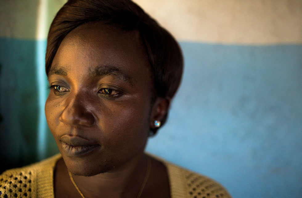 Demokratische Republik Kongo: Eine Frau blickt traurig an der Kamera vorbei. Hinter ihr ist eine blau-weisse Wand zu sehen. 