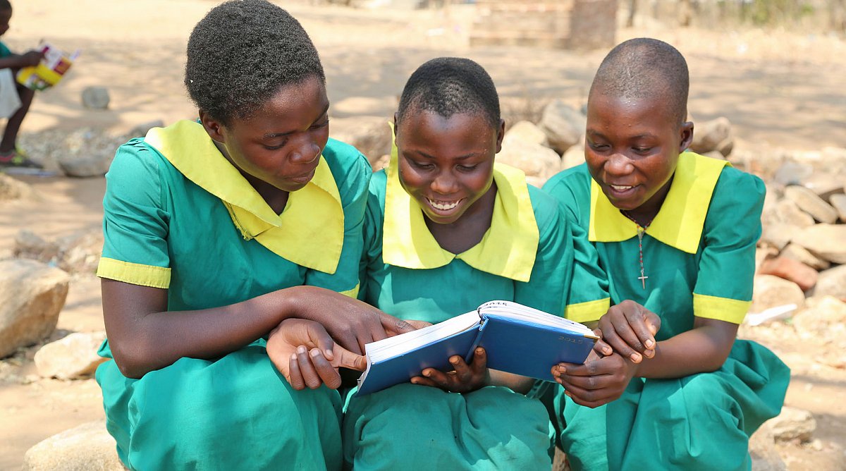 Drei Mädchen in Malawi lesen in einem Buch.