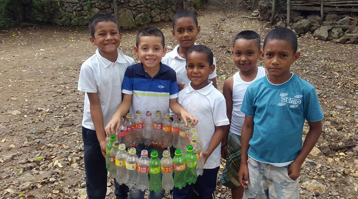 Nicaragua: Sechs Buben blicken lächelnd in die Kamera. Einer der Jungs hält einen selbstgebastelten Kranz aus bunten PET-Flaschen in den Händen.