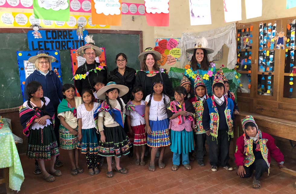 Bolivien: Schweizer Paten besuchen eine Klasse mit Mädchen und Buben in traditionellen Trachten.